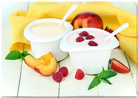 Yoghurt waters fruits and pieces of fruit with yellow napkin on a table